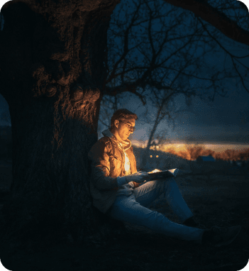 Person reading at night under a tree